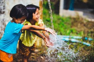 Dos niñas jugando con el agua de una fuente