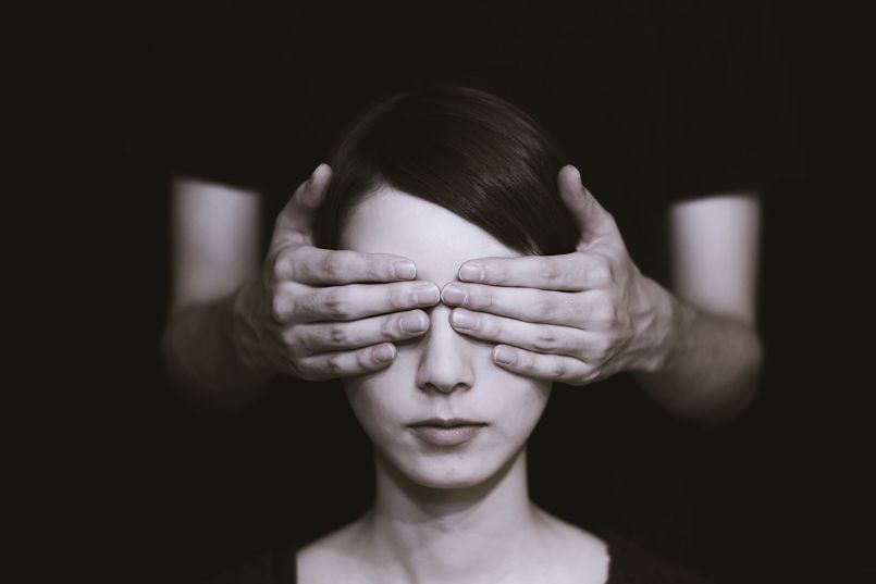 Unas manos tapan los ojos del rostro de una mujer